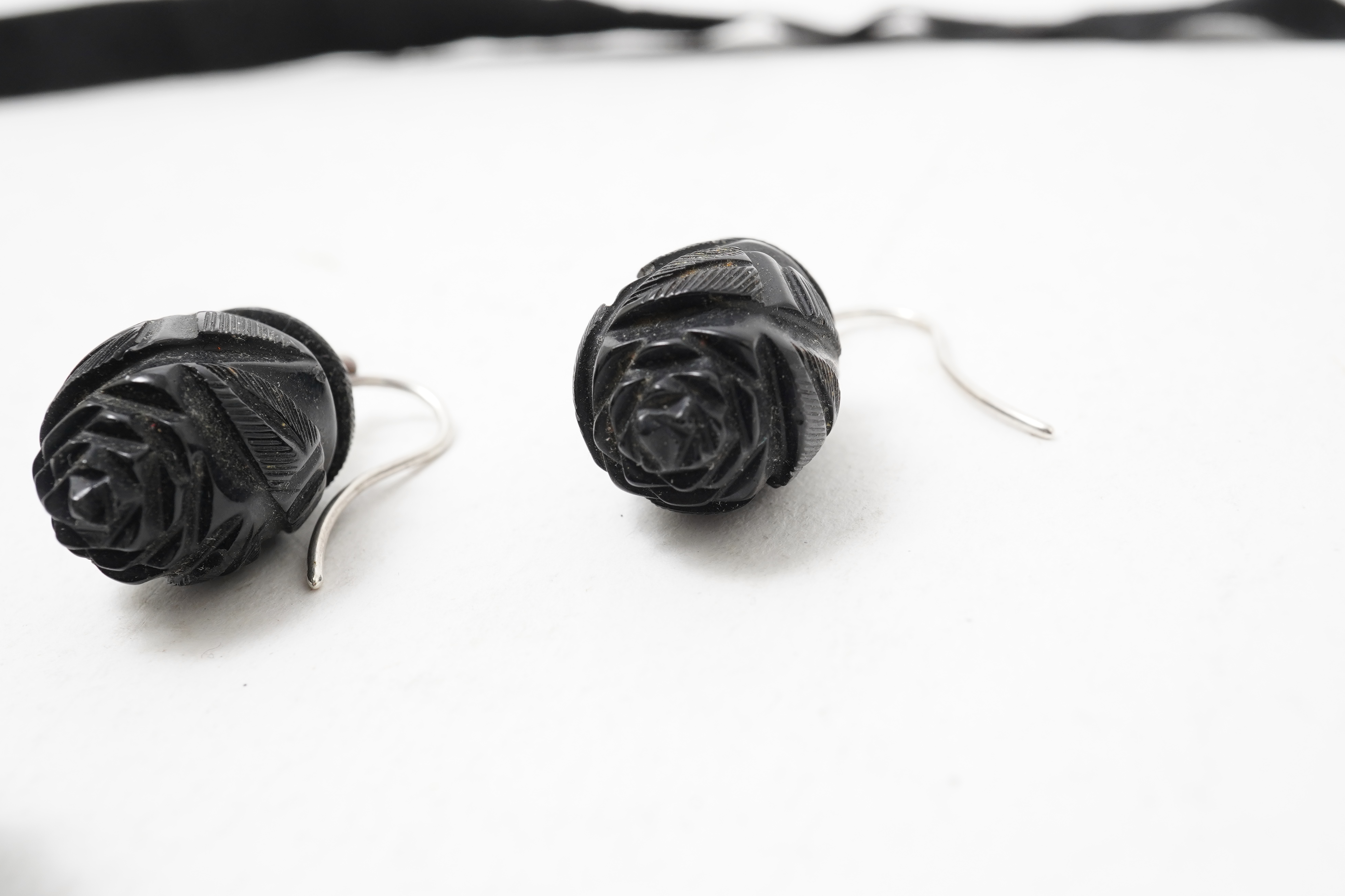 A collection of jewels, comprising: a moulded bog oak brooch depicting a hand holding a posy, length 7.4cm; a carved jet brooch depicting a Gothic ruin, possibly part of Whitby Abbey; a necklace composed of polished pane